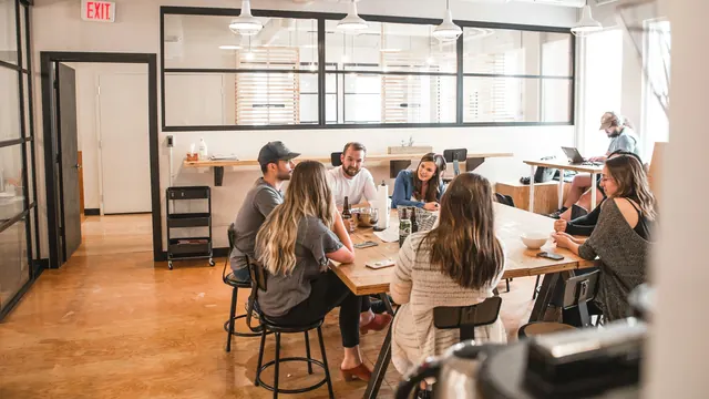 A small group talks together around a table in a bright shared workspace.