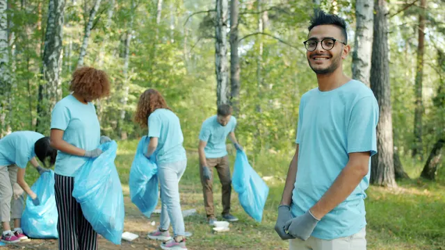 Smiling volunteers in matching shirts work together outdoors on a sunny day.